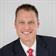 Professional headshot of man in suit and red tie